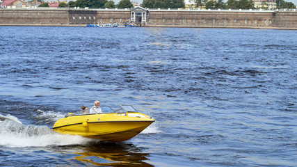 A yellow pleasure boat sails along the canals of the city of St. Petersburg, Russia.