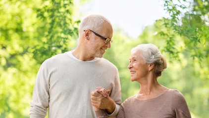 old age and people concept - happy senior couple holding hands over green natural background