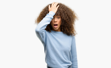 African american woman wearing a sweater surprised with hand on head for mistake, remember error....
