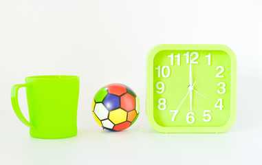 green mug, alarm clock and ball isolated on white background. selective focus.