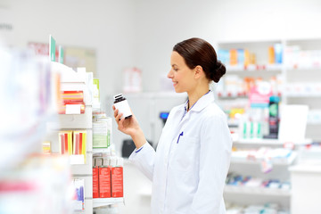medicine, pharmaceutics, healthcare and people concept - happy female apothecary with drug at...