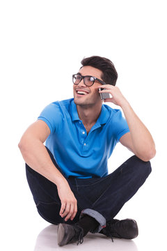 young casual man sitting  and talking on his cell phone