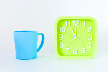 plastic Mug and green square clock isolated on bright background. selective focus.