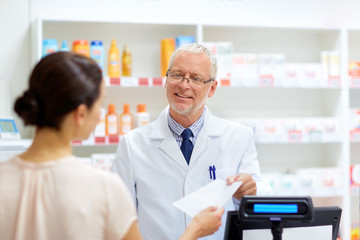 Fototapeta na wymiar medicine, healthcare and people concept - senior apothecary taking prescription from customer at pharmacy