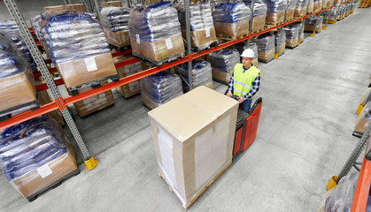 logistic business, shipment and people concept - loader operating forklift and loading boxes at...