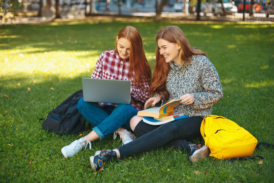 Smiling students studying outdoors on campus 