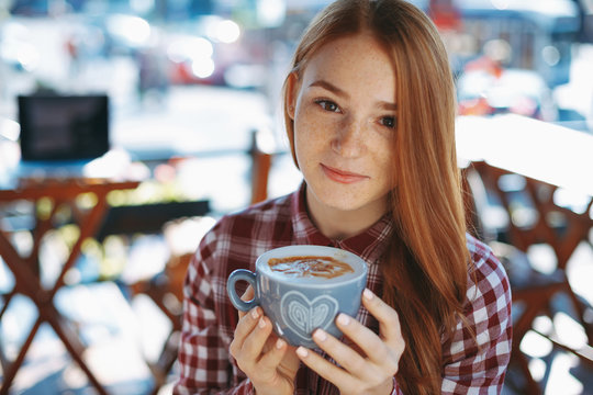 Girl enjoying the coffee aroma while holding the cup with hands