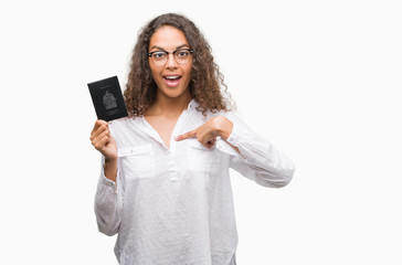 Young hispanic woman holding passport of Canada with surprise face pointing finger to himself