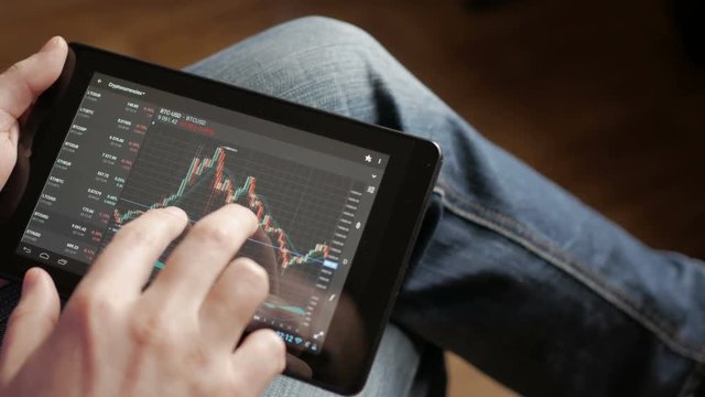 Stock market, trading online, trader working with tablet on stockmarket trading floor. Man touching screen, browse foreign exchange market data, chart. Forex. Crypto currency. Bitcoin cryptocurrency.
