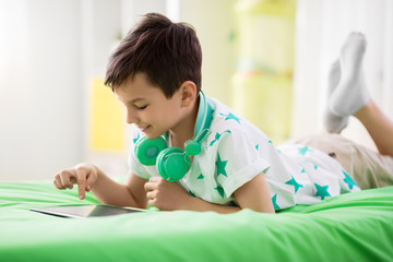 childhood, technology and people concept - boy with tablet pc computer playing game at home