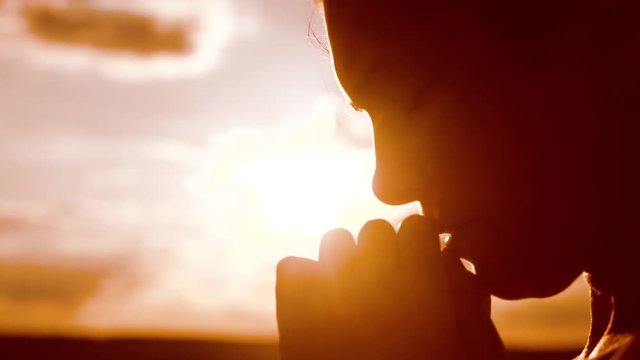 the girl prays. Girl folded her hands in prayer silhouette at sunset. slow motion video. Girl folded her lifestyle hands in prayer pray to God. girl praying asks forgiveness for sins of repentance