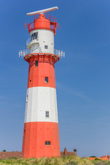 Fototapeta na wymiar Colorful lighthouse on a dune in Borkum, Germany