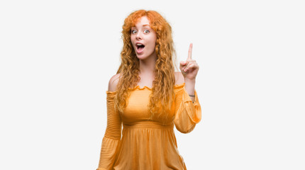 Young redhead woman pointing finger up with successful idea. Exited and happy. Number one.