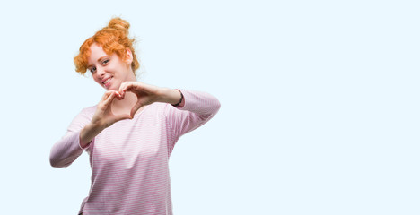 Young redhead woman smiling in love showing heart symbol and shape with hands. Romantic concept.