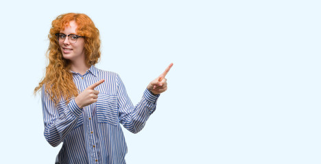 Young redhead bussines woman smiling and looking at the camera pointing with two hands and fingers...