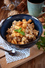 Porridge with apples and cinnamon topped with mint in a blue bowl. British cuisine meal