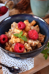 Porridge with apples, raspberries and honey topped with mint. Healthy breakfast meal