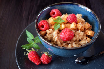 Porridge with apples, raspberries and honey topped with mint. Healthy breakfast meal