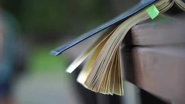 Wind turns the pages of open Notebook lies on wooden handrail in park, business concept