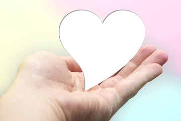 White for text heart shape lay on hand with colorful background. Valentine day. Yellow pink aqua blurred