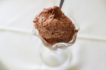 Chocolate mousse with a spoon in portion glasses on white table.
