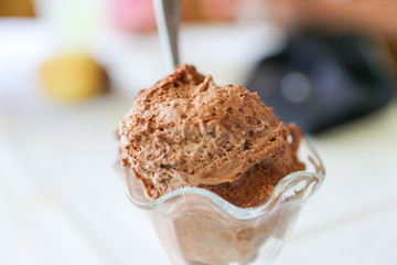 Chocolate mousse with a spoon in portion glasses on white table.