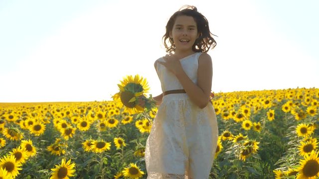 Happy little girl running happy free across the field with sunflowers. slow motion video. smelling big sunflower on summer field. Delight of lifestyle a pleasant smell. Summer holiday. concept