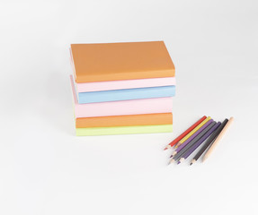 colored pencils and stack of books on white background. photo wi