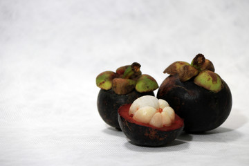 Two mangosteen and one peel on white background. It is queen of fruits.