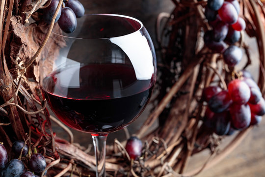 Glass of red wine with grapes and dried  leaves.