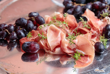Italian prosciutto crudo or jamon with thyme and grapes.