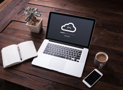 View of Cloud upload processing data on laptop with internet with office equipment and smartphone on wooden desk background