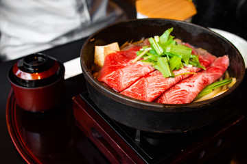 Tasty and delicious Japanese Sukiyaki nabe with best-quality cuts of thinly sliced sirloin or rib eye or tenderloin Kuroge Wagyu beef in a cast iron pan. Top and highest Marble Score. Natural light.