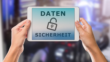 Hands holding tablet with data security written in german on it and colorful media background