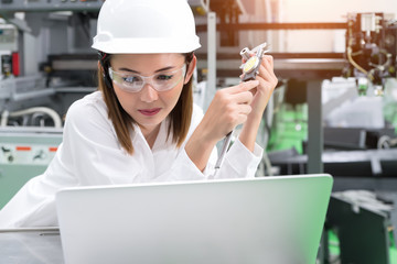 Young woman engineer working on machine in factory