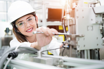 Young woman engineer working on machine in factory