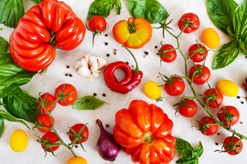 Cherry tomato branch, garlic, fresh basil, pepper on a light background. Ingredients for making sauces. Italian Cuisine.