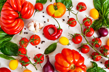 Cherry tomato branch, garlic, fresh basil, pepper on a light background. Ingredients for making sauces. Italian Cuisine.