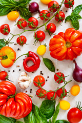 Cherry tomato branch, garlic, fresh basil, pepper on a light background. Ingredients for making sauces. Italian Cuisine.