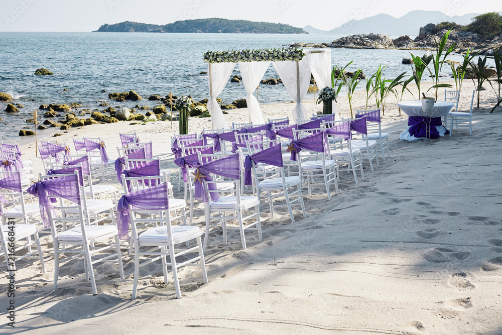 Wall mural Beach wedding venue settings with white chiavari chairs decorate with violet organza sash at seaside