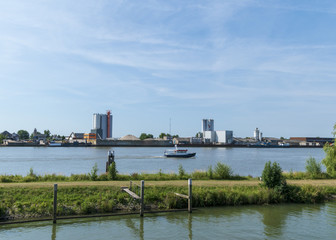 River with factory on the bank and passing boat. Schoonhoven, The Netherlands.