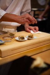 Obraz na płótnie Canvas Professional and experienced sushi chef carefully add final touch with confident and dedication to his perfect sushi. Precision and Finesse at its best practice to achieve top performance in business.