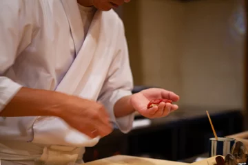 Fotobehang Professionele sushichef die zorgvuldig de juiste druk gebruikt om met vertrouwen en toewijding perfecte sushi te maken. Precisie en finesse op zijn best om topprestaties in het bedrijfsleven te bereiken. © wanessa_p