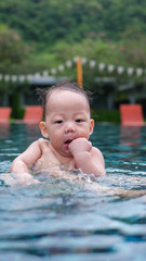 The Asian cute baby likes to swim and play in swimming pool.