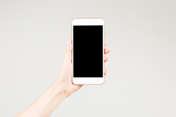Fototapeta na wymiar Female holding white smartphone with blank screen in here left hand