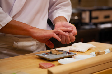 Chef de sushi professionnel utilisant soigneusement la bonne pression pour faire des sushis parfaits avec confiance et dévouement. Précision et finesse à sa meilleure pratique pour atteindre les meilleures performances en affaires.