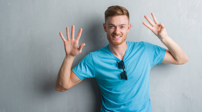 Young redhead man over grey grunge wall wearing casual outfit showing and pointing up with fingers number eight while smiling confident and happy.