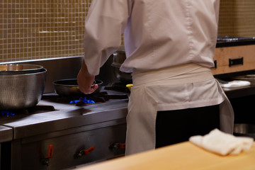 Male Professional and experienced chef is cooking in Japanese kitchen with confident and dedication. Precision and Finesse at its best practice is require to achieve top performance in every business.