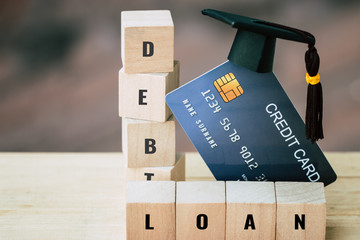 Debt Financial problems for Education Graduate study scholaship concept : Graduation Cap on Mock up Card with wooden blocks word "DEBT, LOAN" Idea for play successs studying or business use so money