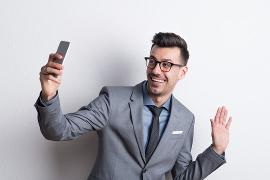 Portrait of a young man with smartphone in a studio, taking selfie.